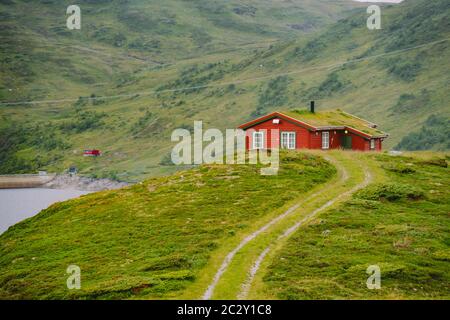 Norwegisches Sommerhaus aus Holz mit Blick auf den malerischen See, Norwegen, Skandinavien. Ferienhaus Am See In Ländlicher Umgebung. Torfdach Hütte am See. T Stockfoto