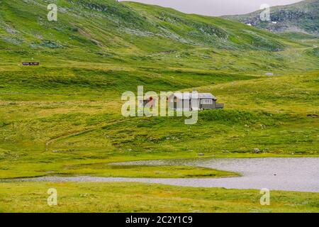 Norwegisches Sommerhaus aus Holz mit Blick auf den malerischen See, Norwegen, Skandinavien. Ferienhaus Am See In Ländlicher Umgebung. Torfdach Hütte am See. T Stockfoto