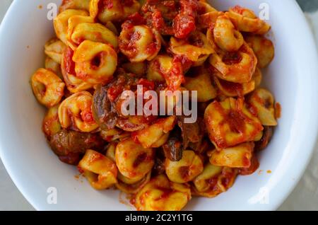 Nahaufnahme einer weißen Schüssel gefüllte Pasta ( Ravioli ) mit einer Tomatensauce und Pilzen Stockfoto