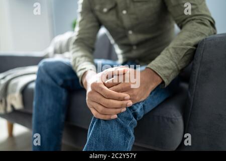 Menschen leiden unter Knieschmerzen Sitzen auf einem Sofa Stockfoto