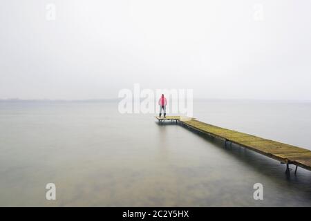 Mann auf Holzsteg am Großen Plöner See / Grosser Plöner See / Grosser Plöner See im Winter, Schleswig-Holstein, Deutschland Stockfoto
