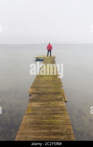 Mann auf Holzsteg am Großen Plöner See / Grosser Plöner See / Grosser Plöner See im Winter, Schleswig-Holstein, Deutschland Stockfoto