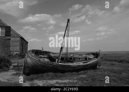 Altes hölzerner Segelboot an der Nord Norfolk Küste UK mit offener Küste und Himmel in schwarz und weiß befahren Stockfoto