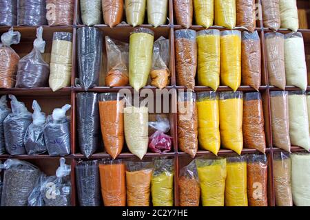 Orientalische Gewürze und Gewürze in transparenter Verpackung auf den Regalen des Shops. Reichtum des östlichen Marktes. Zutaten für köstliche Lebensmittel auf dem Markt zum Verkauf. Stockfoto