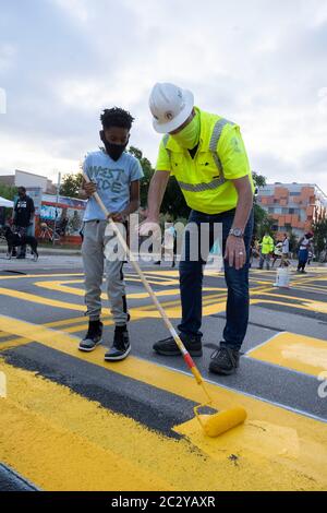 Robert Spillar, Verkehrsdirektor der Stadt Austin, lehrt Tobias Jackson-Woods, wie man eine Malrolle benutzt, um ein Wandbild in der East 11th Street in der Nähe der Innenstadt von Austin zu malen, das "Black Artists Matter" sagt, zwei Tage nachdem die Gruppe "Black Austin Matters" in großen gelben Buchstaben auf der Congress Avenue in gemalt hatte Das Herz der Innenstadt. Stockfoto