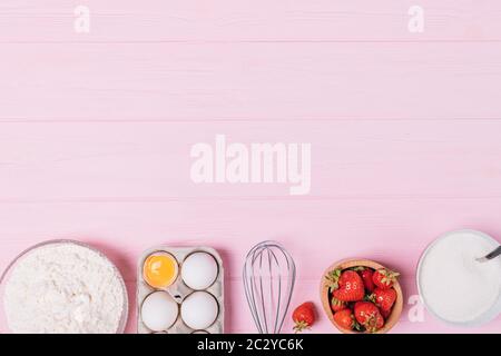 Erdbeerkuchen Backzutaten auf rosa Tisch, flach legen. Stockfoto