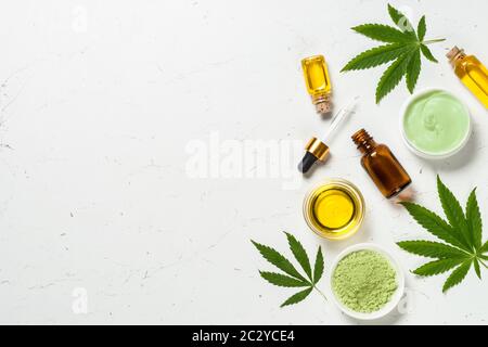 Cannabisöl und grüne Blätter am weißen Tisch. Stockfoto