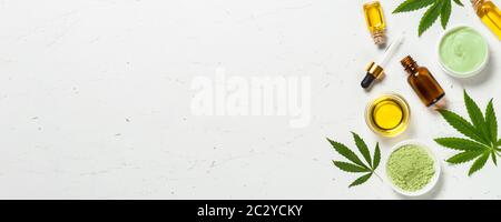 Cannabisöl und grüne Blätter am weißen Tisch. Stockfoto