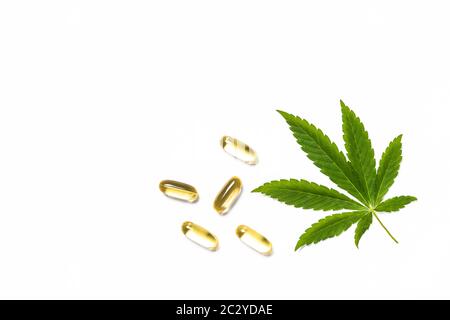 Cannabisöl, Pillen und grüne Blätter am weißen Tisch. Stockfoto
