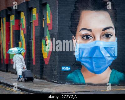 Person, die an Gesichtsmaske Graffiti-Kunst auf der Londoner Straße vorbeigeht, während die Coronavirus-Sperre aufgehoben wird Stockfoto