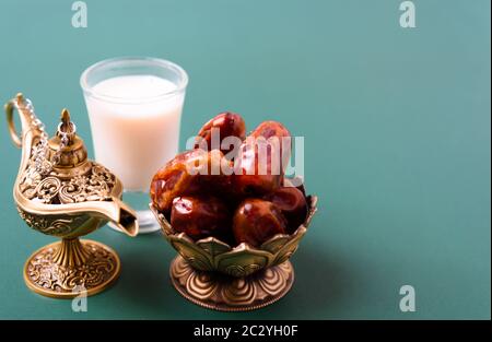 Ramadan, Datteln in goldener Schüssel, Milch, arabian Aladdin goldener Lampe Vintage-Stil auf schwarz-grünem Hintergrund Stockfoto