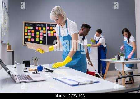 Gruppe von Hausmeister in Uniform Reinigung das Amt mit der Reinigung der Ausrüstung Stockfoto