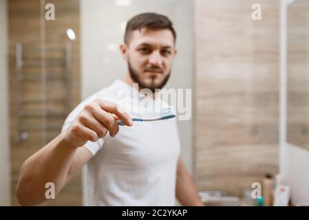 Mann putzt seine Zähne im Bad, Frontansicht im Gesicht, Routine-Morgenhygiene. Männliche Person am Waschbecken führt Haut und Körper Behandlung Verfahren Stockfoto