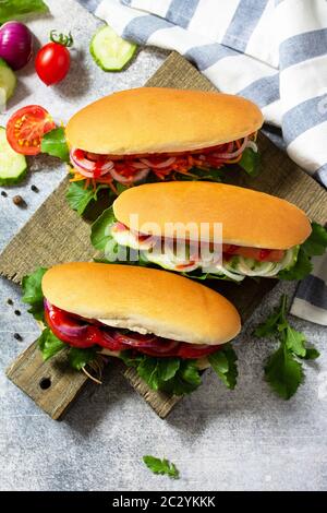 Fast Food. Hot Dog mit Grillwurst und frischem Gemüse auf einem hellen Stein- oder Schiefertisch. Stockfoto