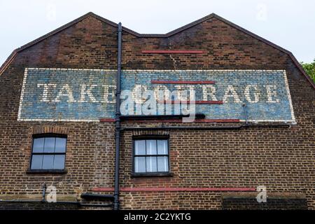 Blick auf das alte Take Courage Geisterschild, das sich in der Redcross Street in London, Großbritannien, befindet. Stockfoto