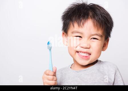 Nahaufnahme asiatisches Gesicht, Kleine Kinder Junge Hand hält Zahnbürste, die er selbst Zähne auf weißem Hintergrund mit Kopierraum, medizinischer Versorgung putzt Stockfoto