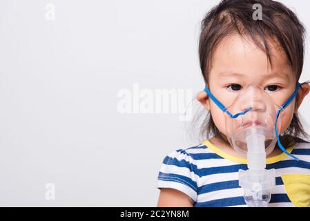 Nahaufnahme asiatisches Gesicht, Kleines Mädchen krank sie mit Dampf-Inhalator-Verneblermaske Inhalation sich auf weißem Hintergrund mit Kopierraum, Gesundheitsmedica Stockfoto