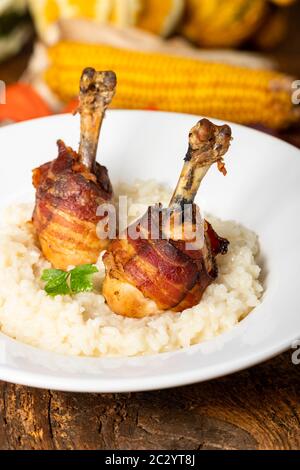 Hähnchenschenkel mit Speck auf Risotto Stockfoto
