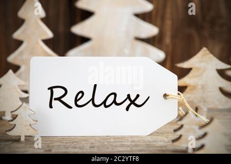 Etikett mit englischem Text entspannen. Weiß Holz- Weihnachten Baum als Dekoration. Braun Holz- Hintergrund Stockfoto