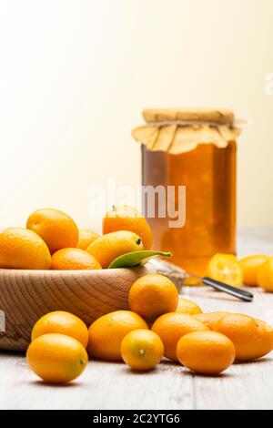 Haufen von kumquat Früchten, chinesische Mandarinen, auf Holztisch mit Marmeladenbecher. Stockfoto