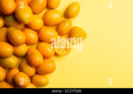 Haufen von Kumquat-Früchten, chinesische Mandarinen, auf gelbem Hintergrund. Stockfoto