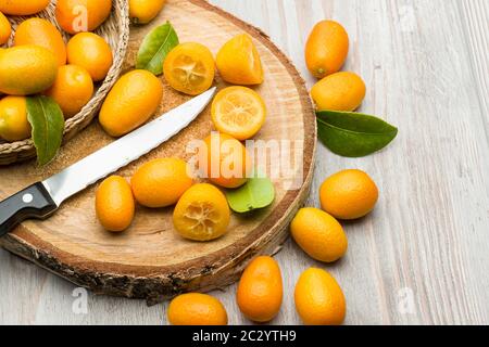 Haufen von Kumquat-Früchten, chinesische Mandarinen, auf Holzschneidebrett. Stockfoto