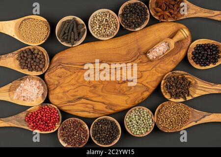 Sechs kleine Holzschüsseln, acht Kochlöffel aus olivem Holz mit verschiedenen Gewürzen und eine Holz-Gewürzschaufel mit rosafarbenem Kristallsalz mit Kopie Stockfoto