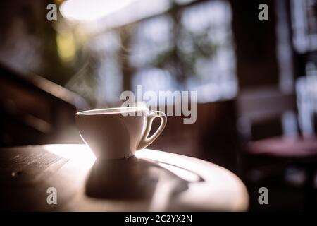 Bild einer dampfenden Tasse Kaffee in der Sonne, mit einer geringen Tiefenschärfe. Stockfoto
