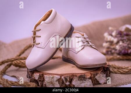 Vintage-Bild von Kinderschuhen. Kinder weiße Lederschuhe auf alten rustikalen Holzhintergrund. Stockfoto