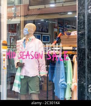 Schaufensterpuppe trägt Gesichtsmaske während Coronavirus, Covid 19 Pandemie. Schild für den Verkauf in der Nebensaison am Schaufenster. Stockfoto