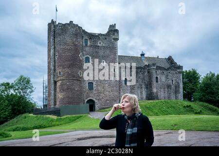 Blonde Touristen in ihren 50er Jahren trinkt einen Schluck Whisky draußen vor Doune Castle, Stirling, Schottland, Großbritannien, Europa Stockfoto