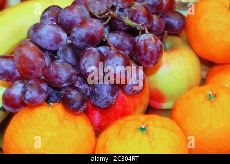 Trauben, Äpfel, Mandarinen und Banane. Hintergrund verschiedener Früchte Stockfoto