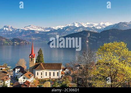 Urlaubsziel am Vierwaldstättersee mit der Pfarrkirche St. Maria hinter den verschneiten Alpen, Weggis, Kanton Luzern, Schweiz Stockfoto