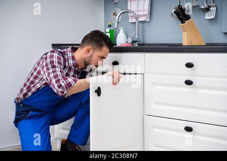 Junge Handwerker zur Festsetzung Waschbecken Tür in der Küche Stockfoto