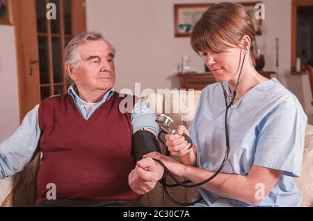 Junge Krankenschwester die Pflege von älteren Menschen zu Hause. Stockfoto
