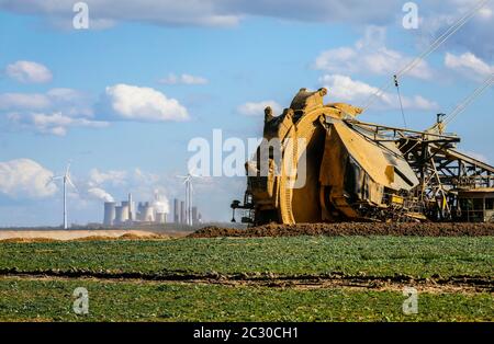 Schaufelradbagger Radbagger im RWE Tagebau Garzweiler gräbt am Abrissrand bei Keyenberg, dahinter ein Wind Stockfoto