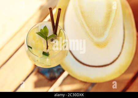 Gurken drink Cocktail, Stroh Hut auf holztisch am Sandstrand Stockfoto