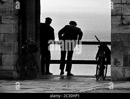 AJAXNETPHOTO. MAI 1969. OLD SALLY PORT, OLD PORTSMOUTH, ENGLAND. - WAS IST DAS! - ZWEI HERREN HABEN SICH ANSTRENGT, EINEN BESSEREN BLICK AUF DIE SICH ABZEICHNENDEN EREIGNISSE ZU BEKOMMEN. DER VIZEADMIRAL HORATIO NELSON SETZTE SICH ZULETZT AUF ENGLISCHEN BODEN, ALS ER DURCH DIESES LOCH IN DEN HEISSEN MAUERN HINDURCH GING, BEVOR ER IM SEPTEMBER 1805 MIT DEM START ZUM HMS-SIEG UND DER SCHLACHT VON TRAFALGAR AUFTRAT. FOTO: JONATHAN EASTLAND/AJAXREF:356917 10A 45 Stockfoto