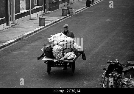 AJAXNETPHOTO. FEBRUAR 1968. PORTSMOUTH, ENGLAND. EIN MANN SCHIEBT EINEN WAGEN, DER MIT ALTEN KLAMOTTEN UND HAUSMÜLL AUF DER ETHEL ROAD IN FRATTON HOCH GESTAPELT IST. FOTO: JONATHAN EASTLAND/AJAX REF:3568133 1  46A Stockfoto