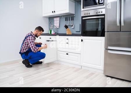 Junge Handwerker zur Festsetzung Waschbecken Tür in der Küche Stockfoto