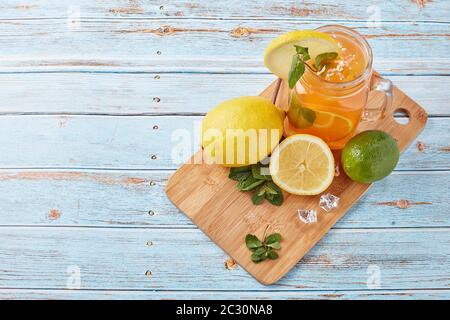 Zitruslimonade mit Eis, Minzblättern, Zitronen- und Limettenscheiben stehen auf einem blauen Holztisch. Hausgemachte Limonade mit Zitrusfrüchten. Gesundes kühles Getränk Stockfoto