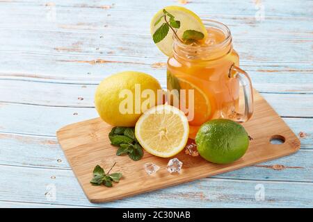 Zitruslimonade mit Eis, Minzblättern, Zitronen- und Limettenscheiben stehen auf einem blauen Holztisch. Hausgemachte Limonade mit Zitrusfrüchten. Gesundes kühles Getränk Stockfoto