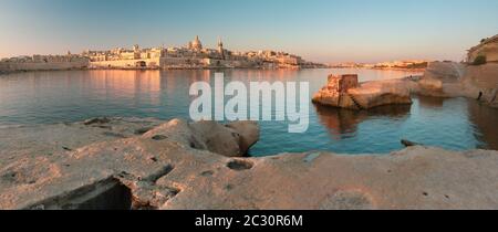 Panorama von Valletta mit Kirchen unserer Lieben Frau vom Berg Karmel und St. Paul's Anglikan Pro-Kathedrale bei Sonnenaufgang aus Sliema, Valletta, Malta Stockfoto