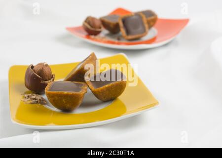 Köstlicher Schokoladenkaramell mit Haselnuss auf gelbem und rotem Teller Stockfoto