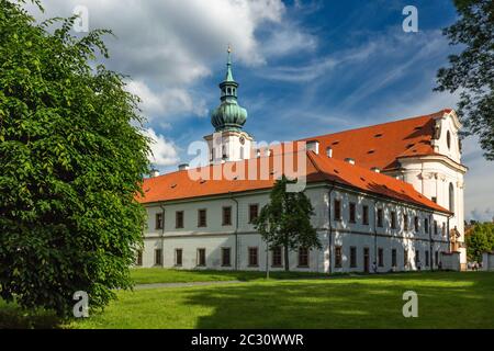 Brevnov, Prag / Tschechien - Juni 11 2020: Blick auf das erste männliche Kloster in Böhmen, das an einem sonnigen Sommertag in einem Park mit grünen Bäumen steht. Stockfoto