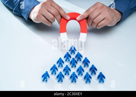 Der Geschäftsmann Hand zieht Team Blau mit Hufeisen Magnet auf weißem Hintergrund Stockfoto