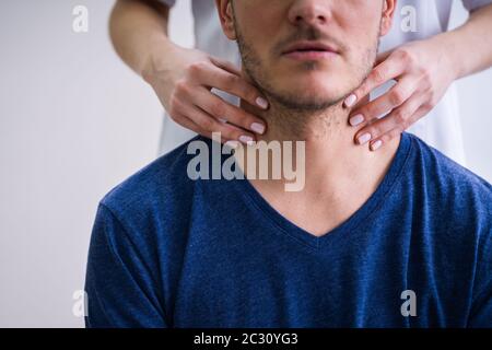 Nahaufnahme Der Hand Eines Arztes, Der Die Kehle Eines männlichen Patienten In Der Klinik Berührt Stockfoto