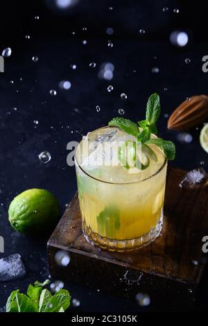 Frische tropische Limonade mit Limette, Orange und Minze auf Schwarz. Vertikales Format. Stockfoto