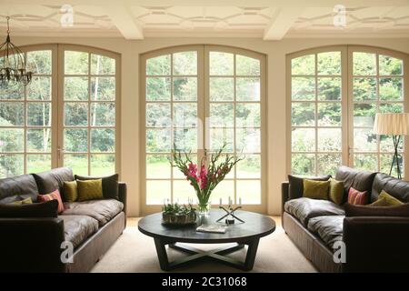 Interieur des großen Wohnzimmers mit französischen Türen, die zu einem üppigen Garten führen Stockfoto