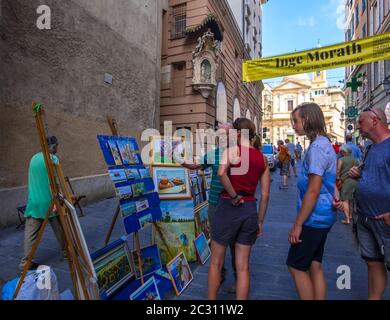 Genua, Italien - 18. August 2019: Künstler, der seine Gemälde auf der Straße in der alten Innenstadt von Genua, Ligurien, Italien verkaufen möchte Stockfoto